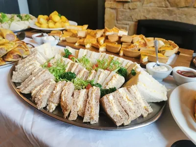 Sandwiches, quiche and sausage rolls laid out on platters for a buffet
