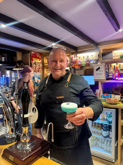 A member of the team behind the bar holding a freshly made cocktail