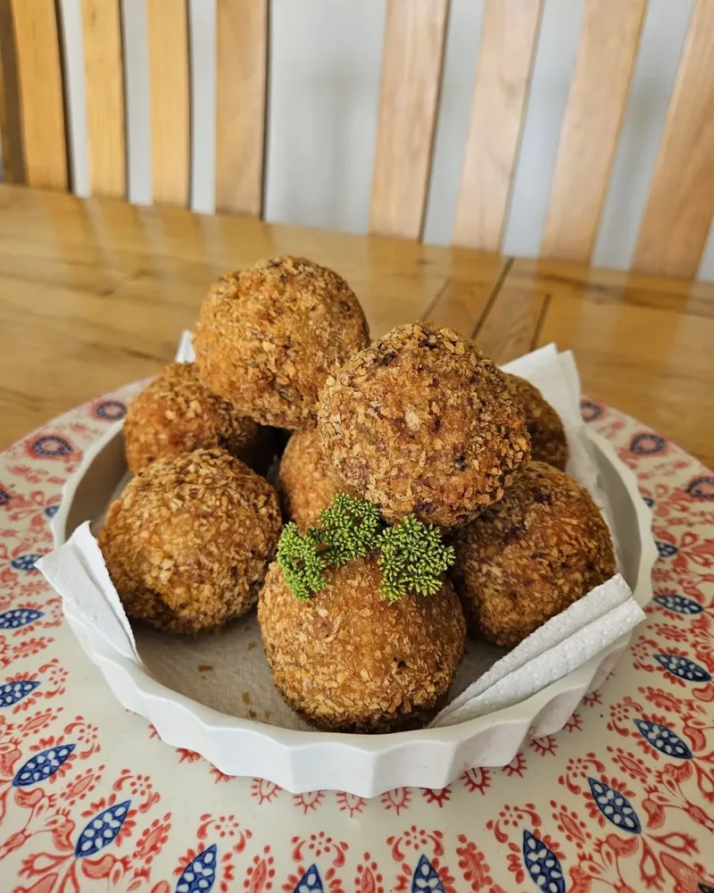 A bowl of crisp breaded scotch eggs garnished with herbs