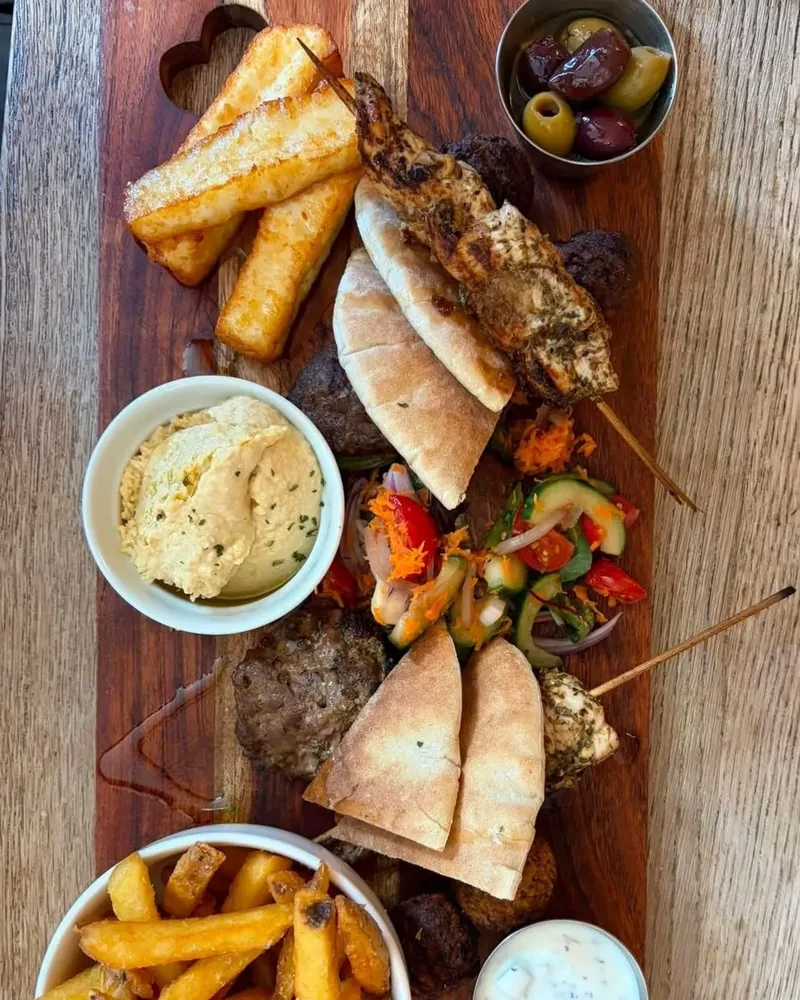 The Greek Board: halloumi, hummus, souvlaki, koftas, pitta, olives, salad and chips on a wooden board